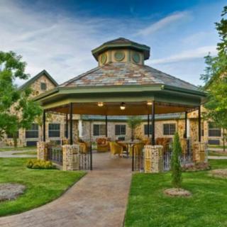 A beautifully designed stone gazebo surrounded by lush greenery and a well-maintained garden.