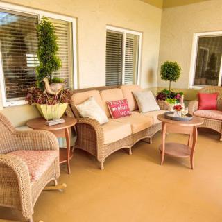 A cozy patio setup with rattan furniture and colorful cushions creates a welcoming outdoor space.
