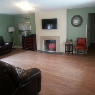 A cozy living room with modern decor, featuring a fireplace and a wall-mounted television.