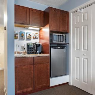 A compact kitchenette with wooden cabinets, featuring a coffee maker and microwave.