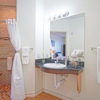 A well-organized bathroom with a sleek vanity, mirror, and shower area.