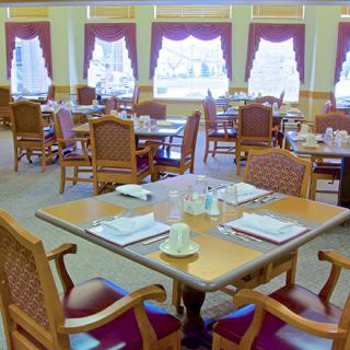 An empty dining room with neatly set tables and chairs by large windows.