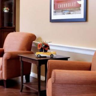 A cozy waiting room with two armchairs flanking a small table, adorned with flowers and a miniature taxi model.