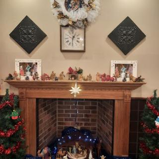 A beautifully decorated Christmas fireplace with a festive mantel featuring stockings, a wreath, and family photos.