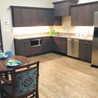 A modern kitchen with sleek cabinets, stainless steel appliances, and a small dining area.