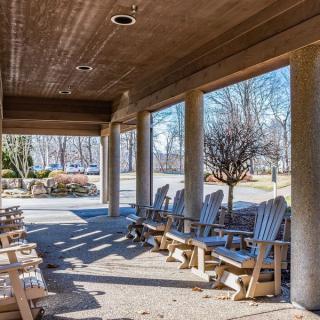 A porch with wooden chairs overlooking a sunny outdoor area.