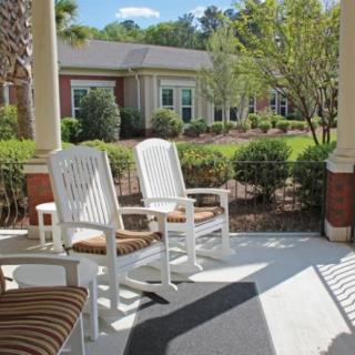 A cozy porch with rocking chairs overlooking a beautifully landscaped garden on a sunny day.