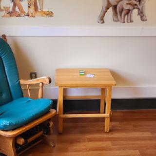 A cozy children's room featuring a rocking chair and a small wooden table.