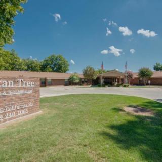 A one-story brick building with a sign on the lawn under a clear blue sky.