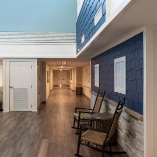 A modern hallway with rocking chairs, featuring blue walls and wood flooring.