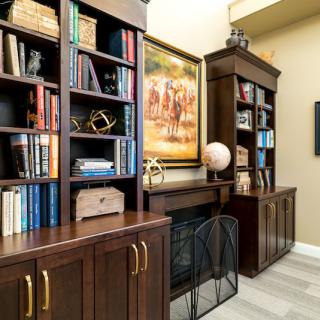 A cozy home library with wooden bookshelves, filled with books and decorative items.