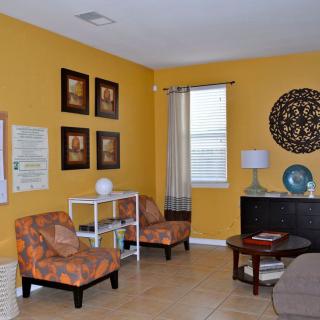 A cozy living room with vibrant yellow walls, featuring patterned chairs and decorative artwork.