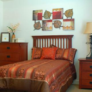A cozy bedroom with a wooden bed frame, decorative pillows, and modern wall art.