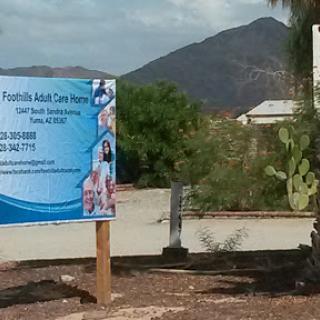 A sign for a residential adult care facility set against a backdrop of mountains.
