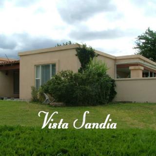 A residential house with a lush green lawn and cloudy sky, labeled 'Vista Sandia'.