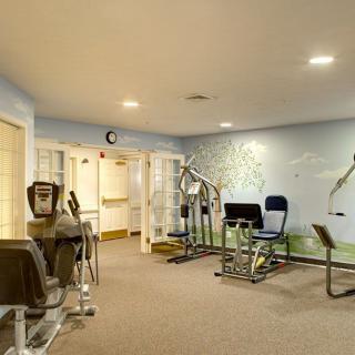 A gym with various exercise machines and equipment in a well-lit room.