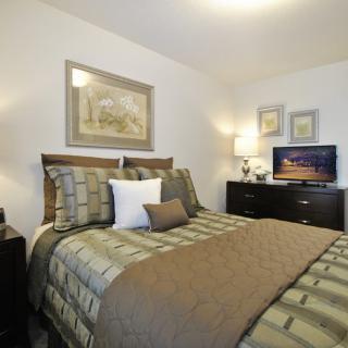 A cozy and well-decorated bedroom with a bed, artwork, and a television.