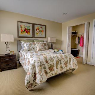 A cozy bedroom with floral bedding, modern lamps, and decorative artwork above the bed.