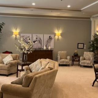 A cozy living room with comfortable sofas, armchairs, elegant lighting, and decorative artwork.