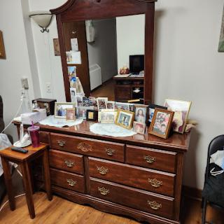 A classic wooden dresser with a mirror, adorned with various photo frames, situated in a cozy room.