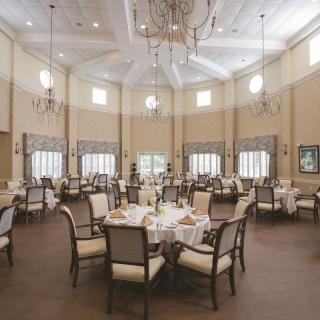 Elegant dining room with neatly arranged tables and chandeliers.