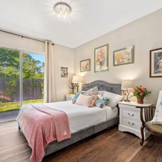 A cozy bedroom with elegant decor, featuring a comfortable bed, nightstands, and ample natural light through a sliding glass door.
