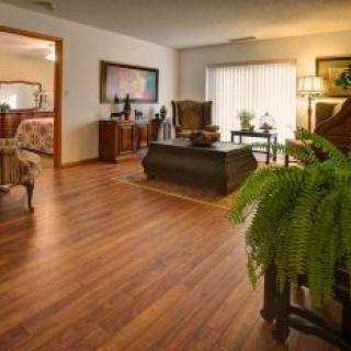 A cozy living room featuring hardwood floors, elegant furniture, and lush indoor plants.