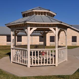 A wooden gazebo with a metal roof situated in an open outdoor area.