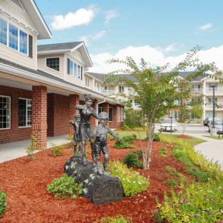 A landscaped garden with statues in front of a suburban building.