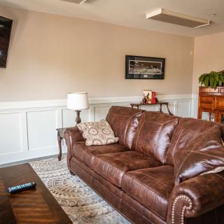 A cozy living room with a leather sofa, adorned with wall art and an indoor plant.