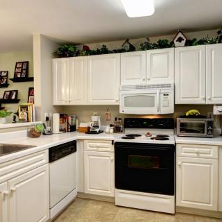 A modern kitchen with white cabinetry and various appliances.