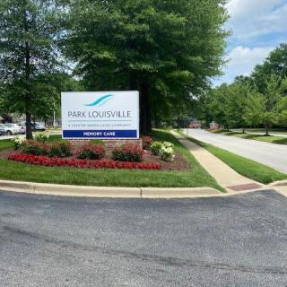 Entrance sign with landscaped surroundings and a driveway.