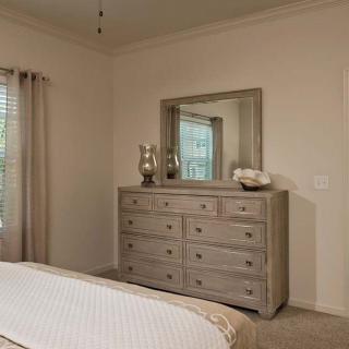 A cozy bedroom featuring a large dresser with a mirror, decorated in neutral tones.