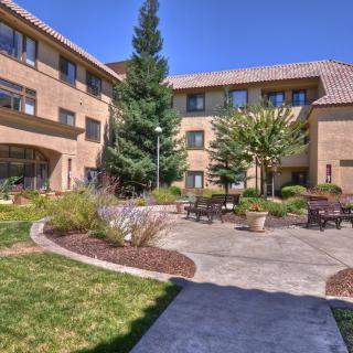 A well-maintained courtyard surrounded by a multi-story building, featuring benches and lush landscaping.