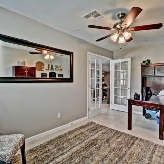 A cozy home office with a ceiling fan, French doors, and a stylish desk.