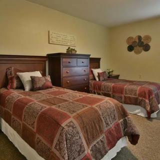 A cozy bedroom featuring two twin beds with patterned bedspreads and a wooden dresser.