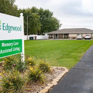 A healthcare facility with a sign for Edgewood Memory Care and Assisted Living, featuring a well-maintained lawn and driveway.