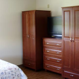 A cozy bedroom featuring wooden furniture, including a wardrobe and dresser, along with a TV.