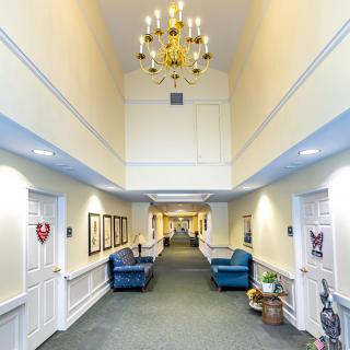 A well-lit hallway with a chandelier, featuring comfortable seating and decorative elements.