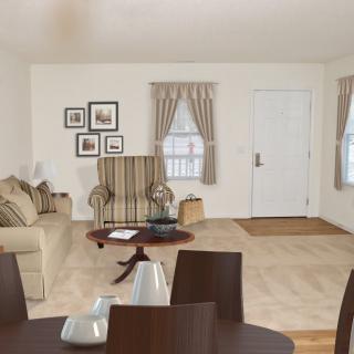 A cozy living room with a sofa, armchair, coffee table, and framed artwork on the walls.
