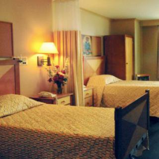A cozy hotel room with twin beds, a television, and warm lighting.