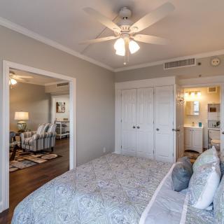 A cozy bedroom interior featuring a bed, ceiling fan, and soft lighting.