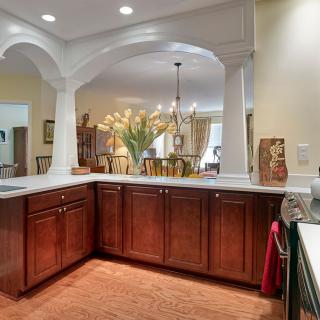 A modern kitchen with wood cabinets and an open layout, featuring elegant decor and lighting.