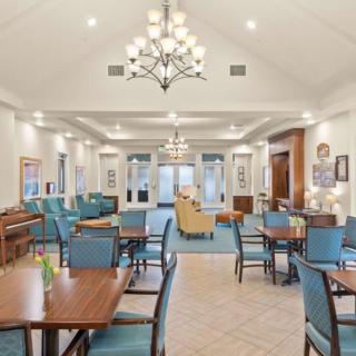 A spacious and elegantly designed dining area with chandeliers, tables, and chairs.