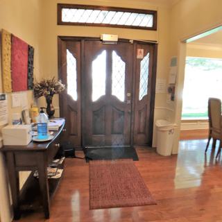 A cozy and welcoming entryway with a wooden front door, small table, and a rug on the wood floor.