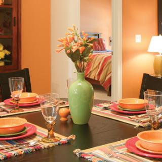 A beautifully set dining table with a green vase of flowers as the centerpiece.