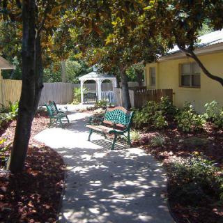 A serene garden pathway with benches and a gazebo surrounded by lush plants.