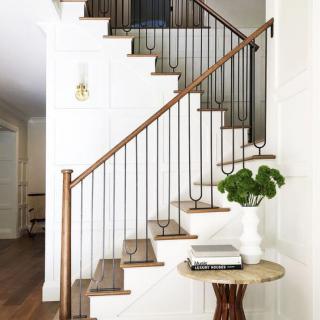 A stylish staircase with wooden steps and a metal railing, complemented by a minimalist table and plant decor.
