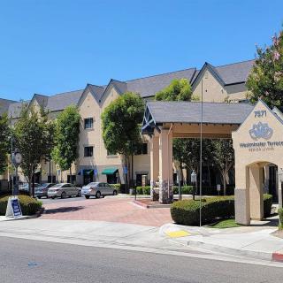A view of a building with an arched entrance and parked cars on a clear day.