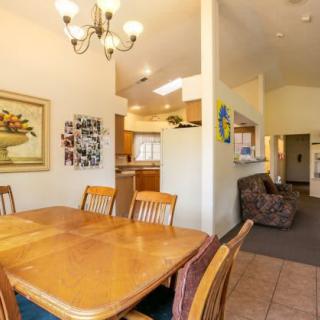 A cozy dining area with wooden furniture, adjacent to a kitchen and living space.